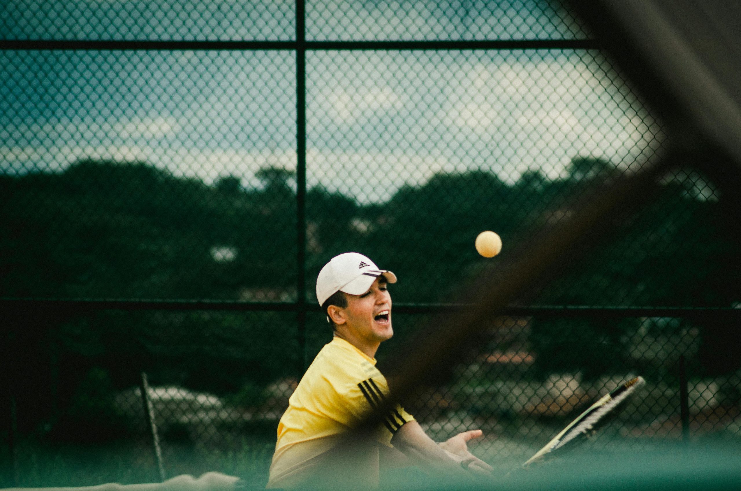 Dynamic action shot of a young man playing tennis on an outdoor court.